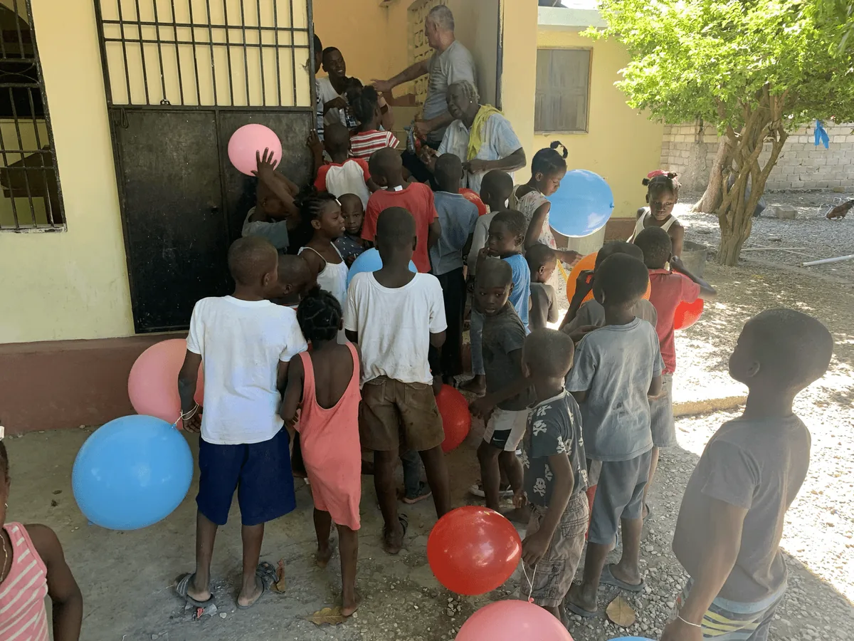 Children with balloons gathered in a sunny courtyard