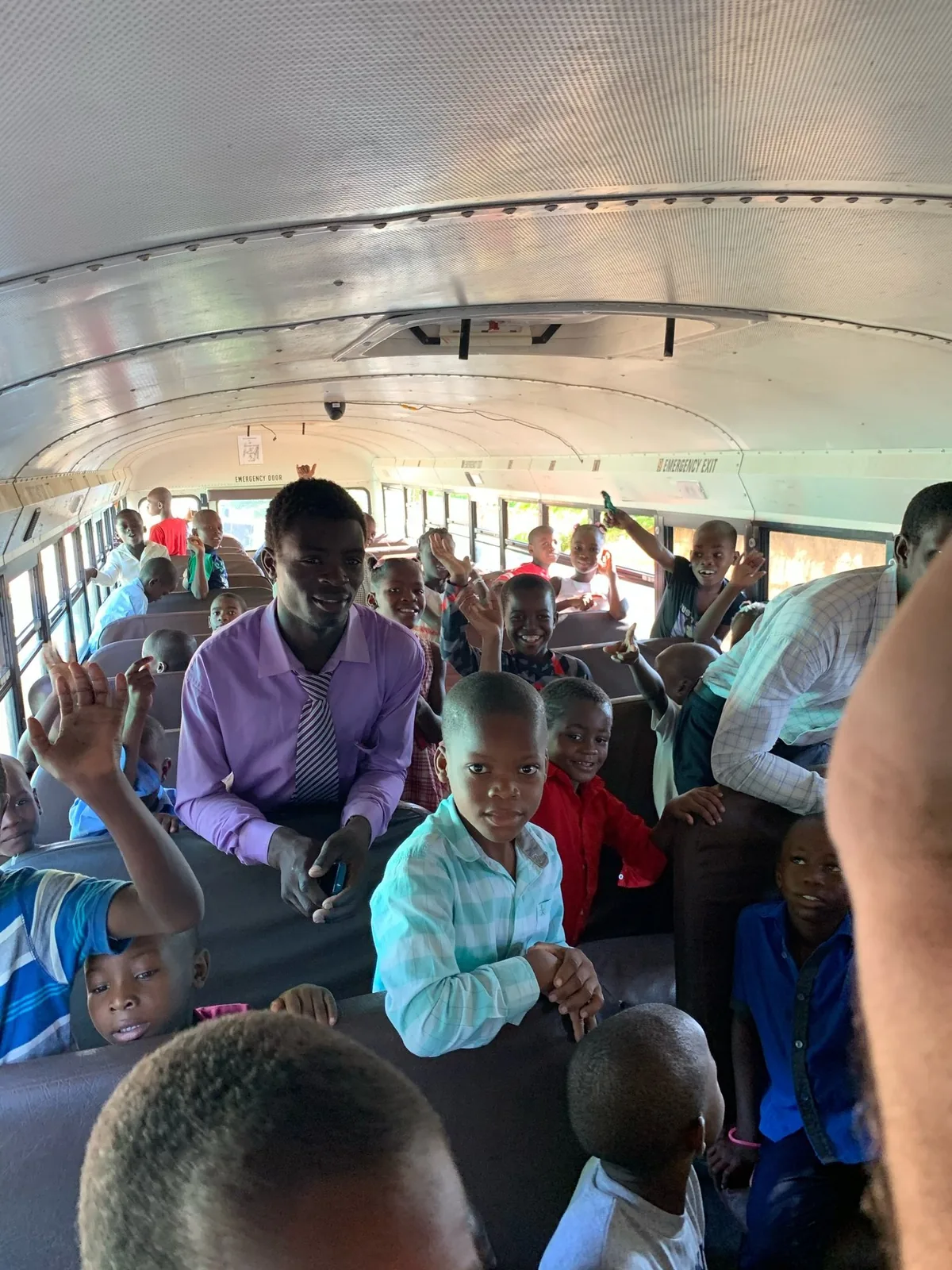 Children waving from their seats on the bus