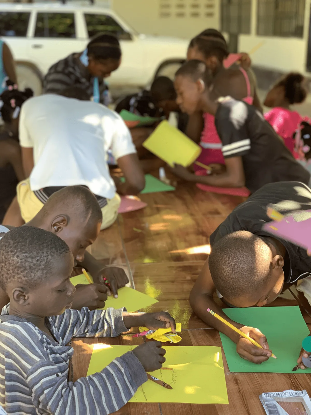 Children cutting and drawing on colored paper at a table